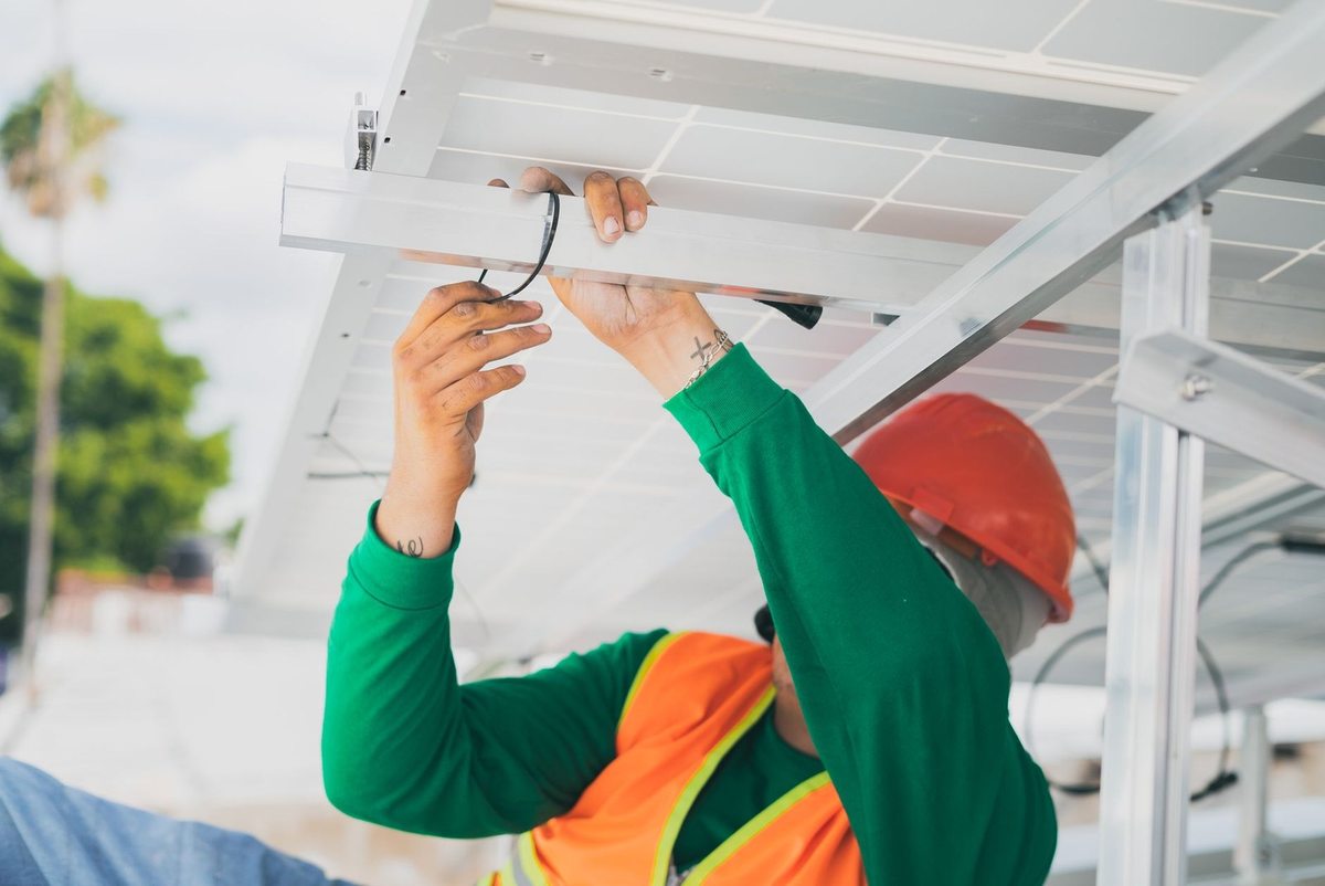 Ouvrier installe des panneaux solaires sur une structure métallique