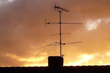 Antenne TV sur une cheminée, silhouette contre un ciel crépusculaire