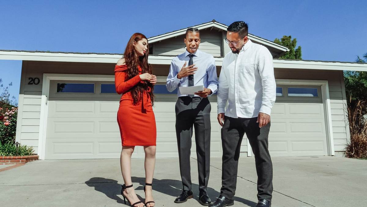 Professionnels devant une maison, agent immobilier présente un document